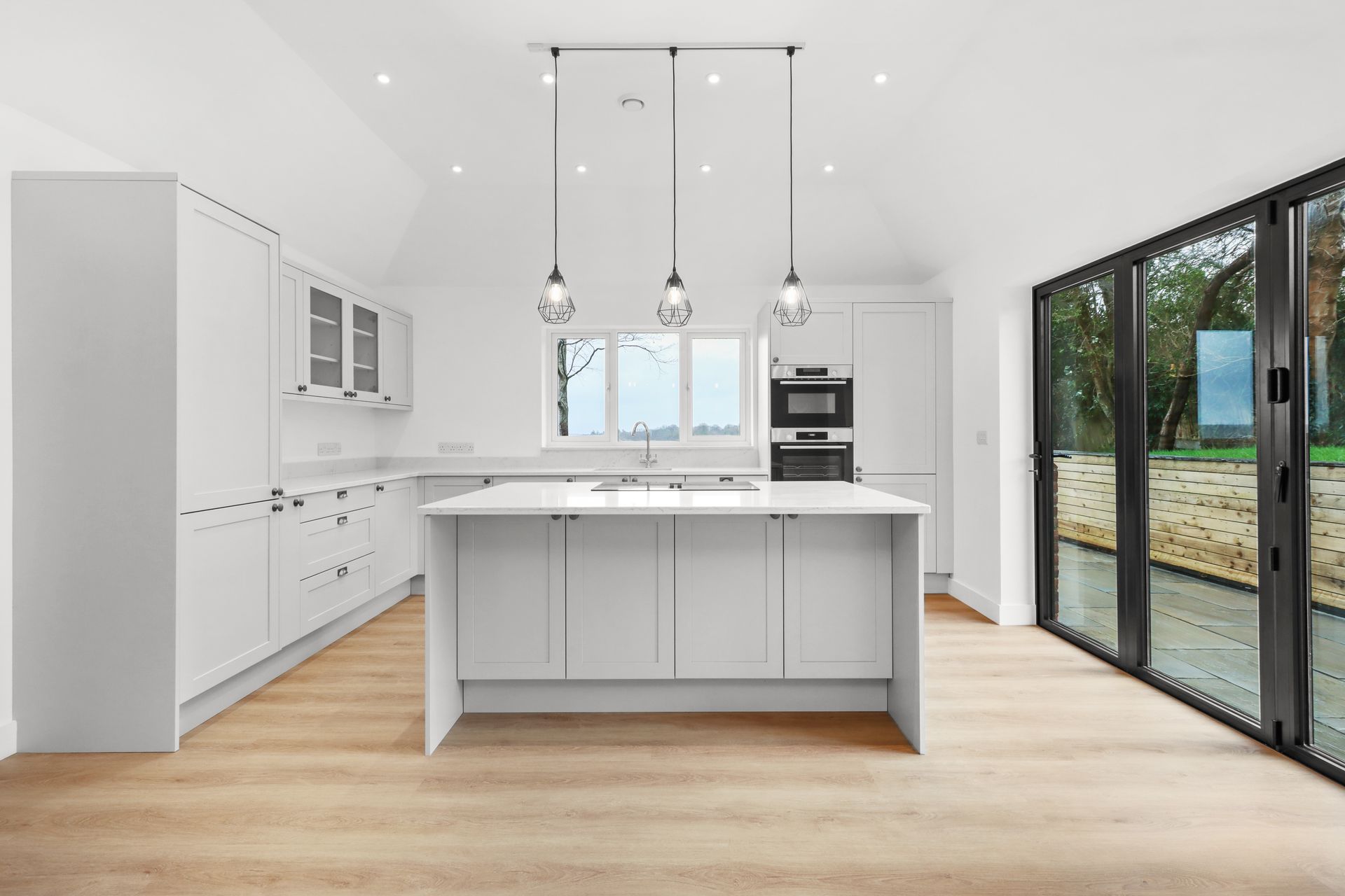 Bramley Barn, Burwash: shaker kitchen with island and bifold doors, by Bramall Homes