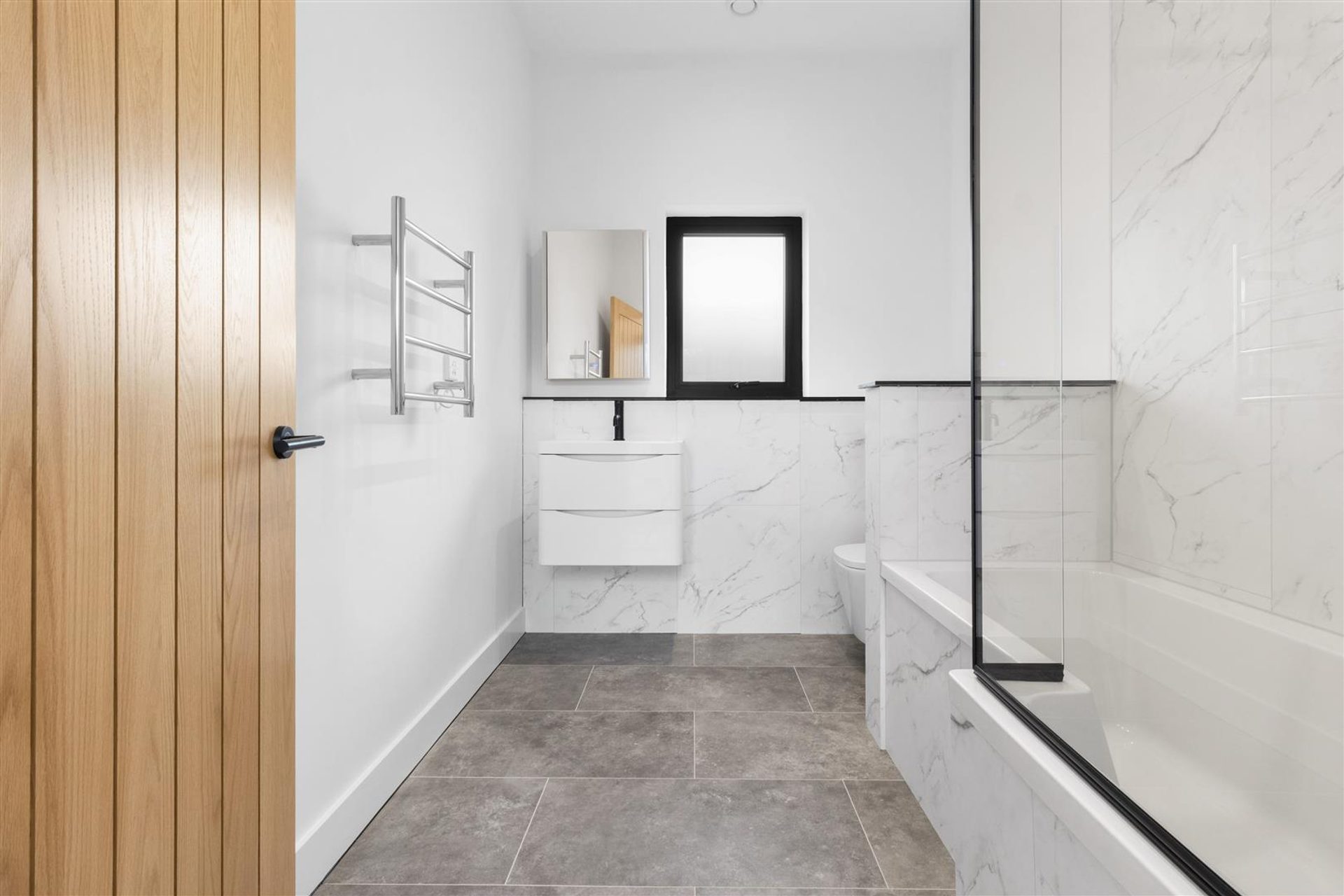 Bridlewood Barn, Horam: bathroom in marble effect tiling with oak door, by Bramall Homes