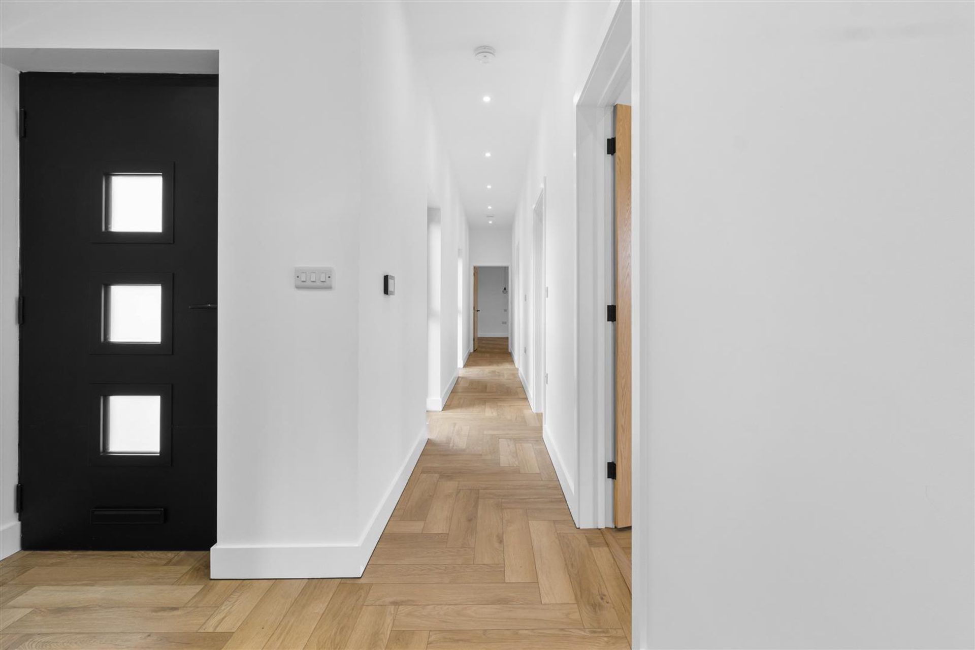 Bridlewood Barn, Horam: hallway with black front door and herringbone flooring, by Bramall Homes