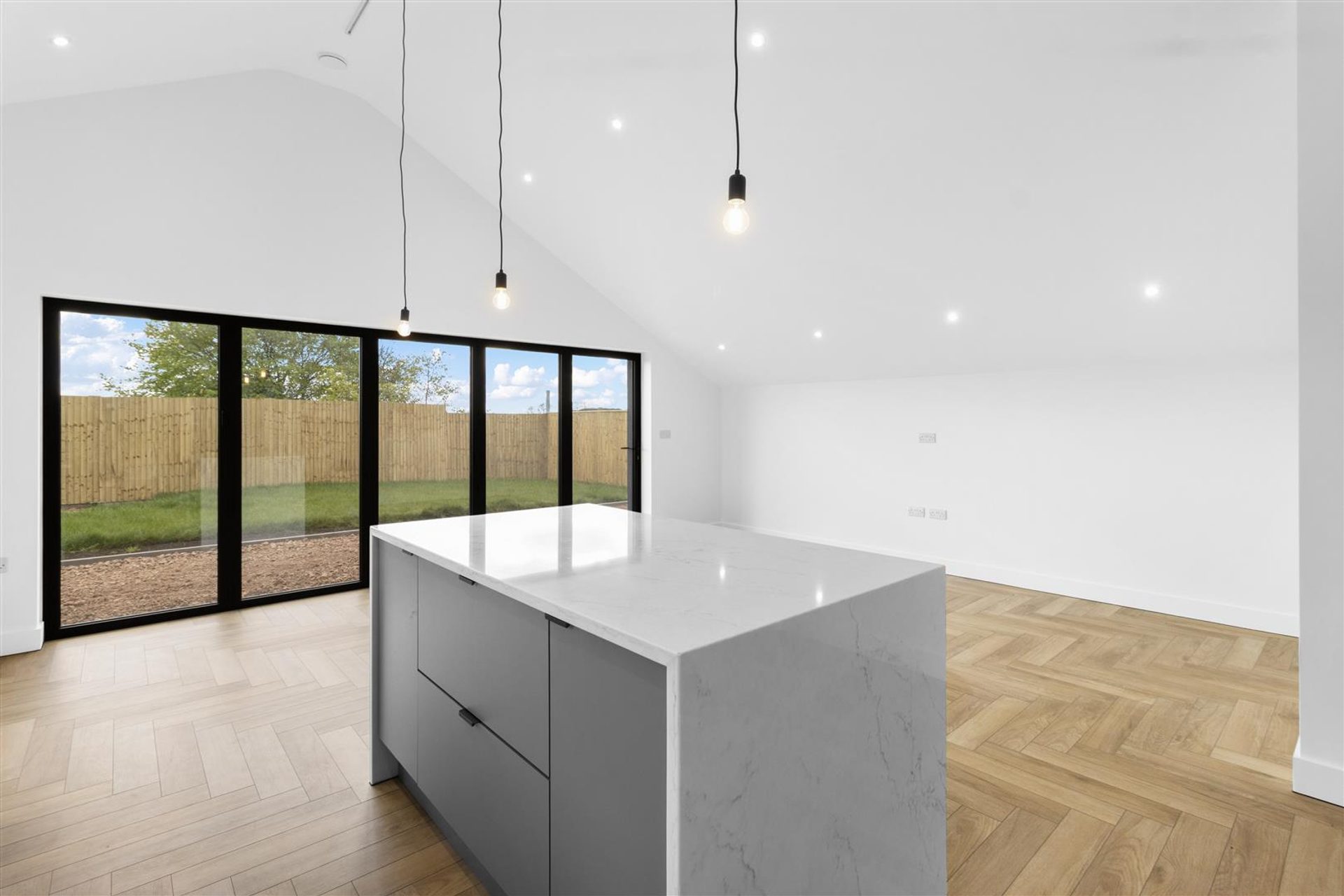 Bridlewood Barn, Horam: kitchen island and bifold doors to the garden, by Bramall Homes